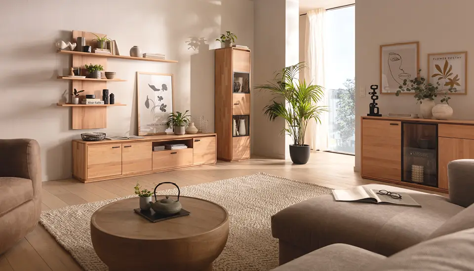 Gemütliches Wohnzimmer mit massiven Holzmöbeln, offener Wandregalgestaltung, Glasvitrine und grünen Pflanzen, sorgt für warme, natürliche Atmosphäre in modernem Einrichtungsstil.